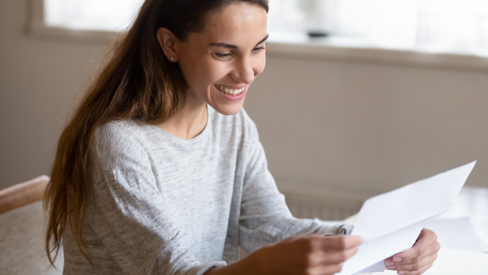 Middle aged woman looking at a piece of paper, smiling